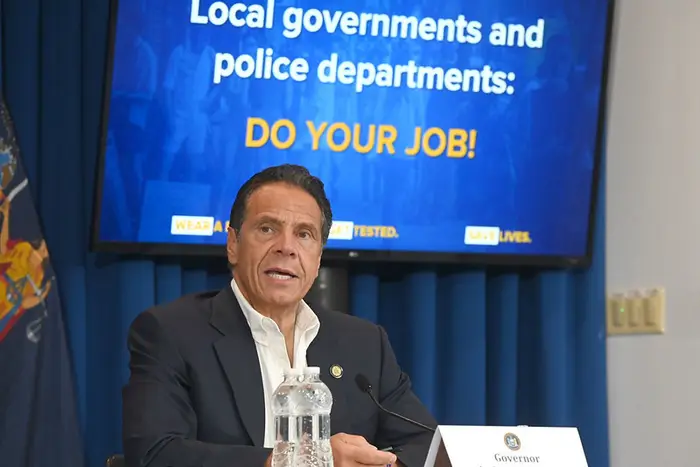 A photo of Governor Andrew Cuomo from July 20th, 2020. He is sitting at a table holding a press conference.